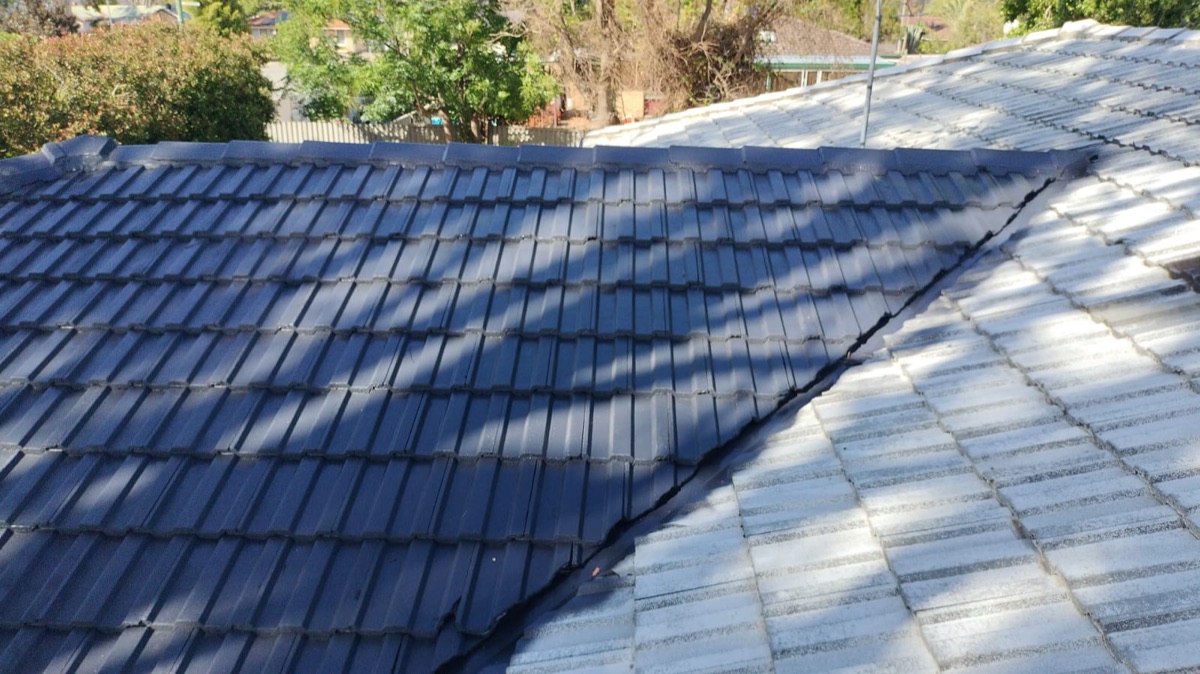 Concrete tile roof half restored to slate grey, half still weathered